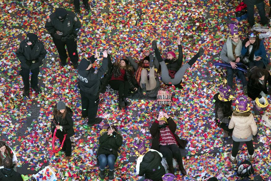 A police officer takes a photo of revelers playing in the confetti during the new year celebration in New York's Times Square as seen from the Marriott Marquis, Sunday, Jan. 1, 2017. (AP Photo/Mary Altaffer)