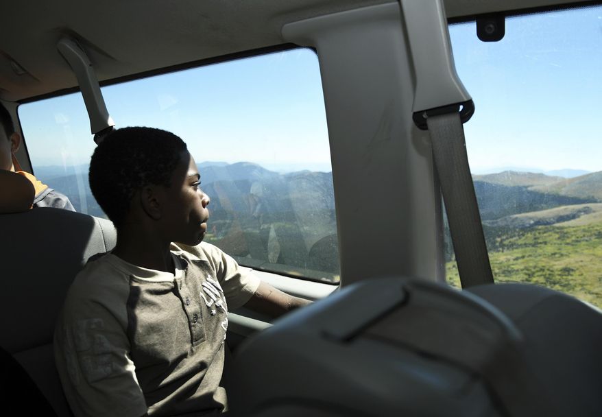 In this Sept. 10, 2016, photo, Justin Mbelechi, a 13-year-old refugee from Africa, peers out of a van that is headed up Mount Evans near Idaho Springs, Colo. He is a member of Boy Scout Troop 1532, which is made up almost entirely of refugees. (AP Photo/Thomas Peipert)