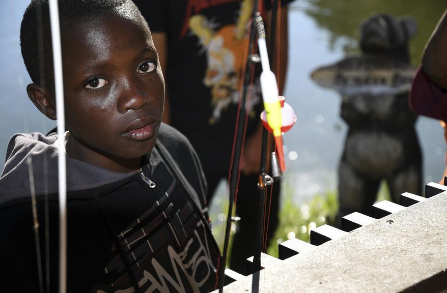 In this Sept. 10, 2016, photo, Gideon Muhigirwa, a 13-year-old refugee from Africa, stands next to a fishing pond near Idaho Springs, Colo. He is a member of Colorado Troop 1532, which is made up almost entirely of refugees. Many of the kids' parents moved to the U.S. with very little money and work long, odd hours, which makes it hard to plan meetings. Troop founder Dr. P.J. Parmar, who recruits kids through his clinic, says many of the scouts have no reliable way to get to the meetings, so he decided to gather only for camping trips. (AP Photo/Thomas Peipert)