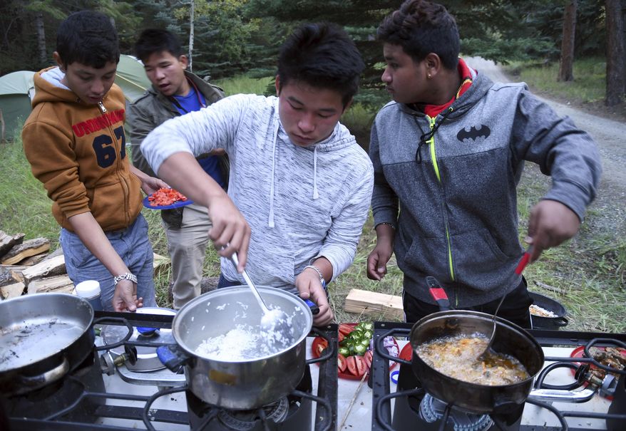 In this Sept. 10, 2016, photo, a group of Nepalese refugees prepare dinner at their campsite in Evergreen, Colo. They belong to Boy Scout Troop 1532, which is made up almost entirely of refugees. At campouts, traditional American food like hot dogs and trail burgers is replaced by fish head stew, fire-roasted corn and Chatpate, a popular Nepalese street snack. S'mores are still a staple. (AP Photo/Thomas Peipert)