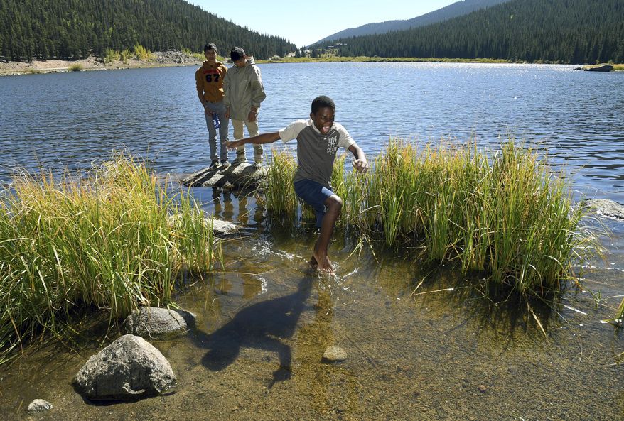 In this Sept. 10, 2016, photo, Justin Mbelechi, a 13-year-old refugee from Africa, jumps through the frigid water of Echo Lake near Idaho Springs, Colo. He is a member of Colorado Boy Scout Troop 1532, which is made up almost entirely of refugees. It's unclear how many of the nation's 2.3 million scouts are refugees, but "few programs are as equipped to help children learn and embrace American culture," Effie Delimarkos, a Boy Scouts of America spokeswoman, said in an email to The Associated Press. (AP Photo/Thomas Peipert)
