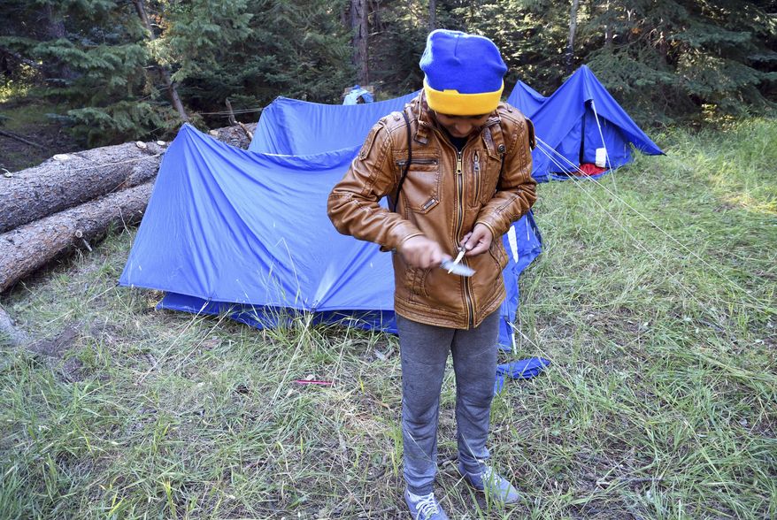 In this Sept. 10, 2016, photo, Tapas Khanal, a 13-year-old refugee from south Asia, whittles a stick at his campsite in Evergreen, Colo. He belongs to a Boy Scout troop in Aurora, Colo., that is made up almost entirely of refugees who hail from far-flung places like Burma, Rwanda and Nepal. (AP Photo/Thomas Peipert)