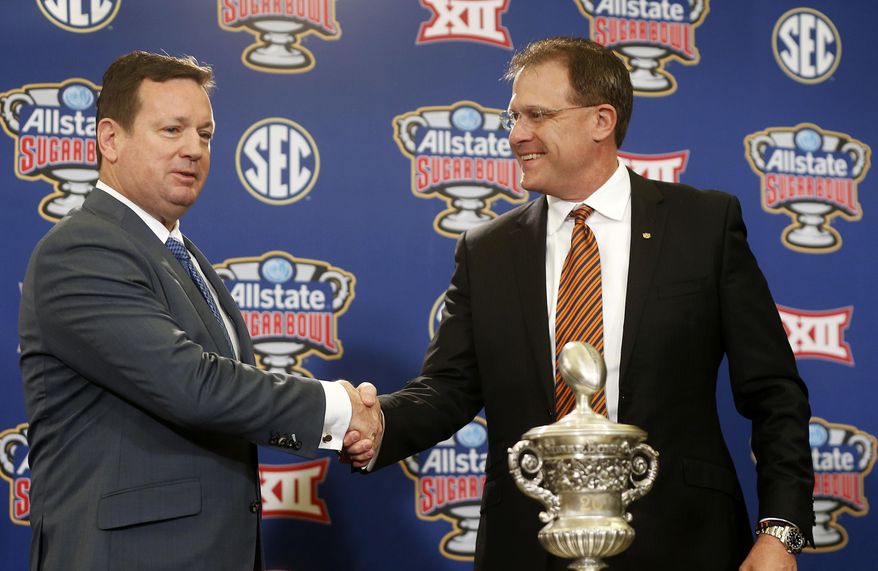Oklahoma head coach Bob Stoops, left, and Auburn head coach Gus Malzahn shake hands during a photo opportunity with the Sugar Bowl trophy in New Orleans, Sunday, Jan. 1, 2017, for the upcoming Sugar Bowl NCAA college football game, which will be played Jan. 2. (AP Photo/Gerald Herbert)