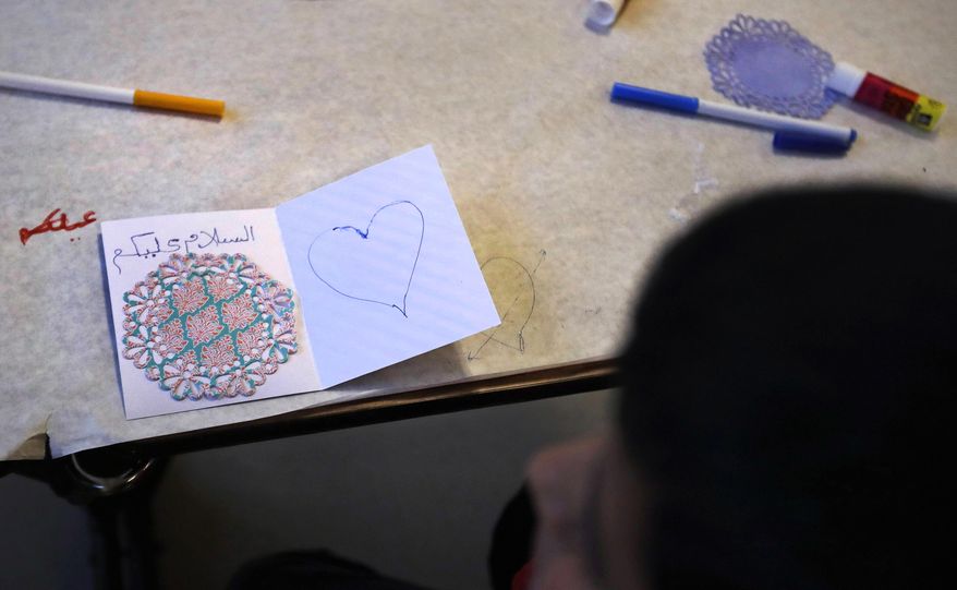 In this Dec. 10, 2016 photo, Syrian refugee Ahmad Alkhalaf sits after completing a card for refugee children displaced in Syria during a day camp for local Muslim children in Sharon, Mass. The young boy who lost his arms in a refugee camp bomb blast is thriving in his new life in Massachusetts. (AP Photo/Charles Krupa)