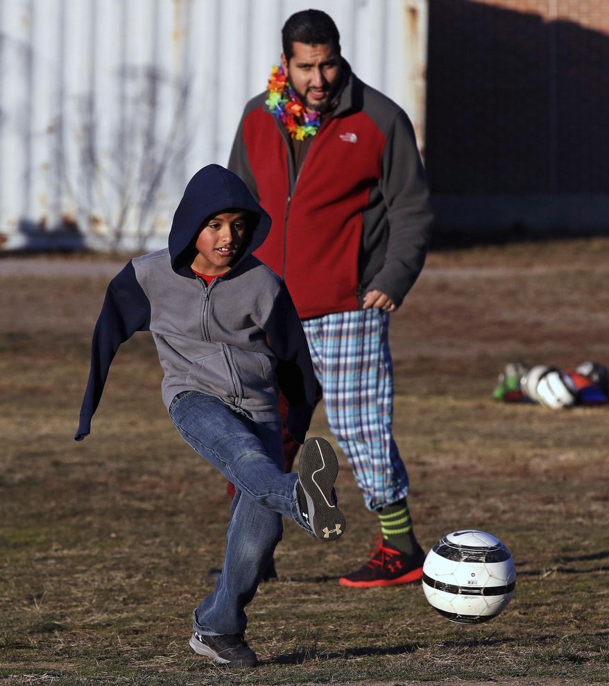 In this Dec. 10, 2016 photo, Syrian refugee Ahmad Alkhalaf plays soccer with friends during a day camp for local Muslim children in Sharon, Mass. The young boy who lost his arms in a refugee camp bomb blast is thriving in his new life in Massachusetts. At rear is camp counsellor Nabil Jalal. (AP Photo/Charles Krupa)