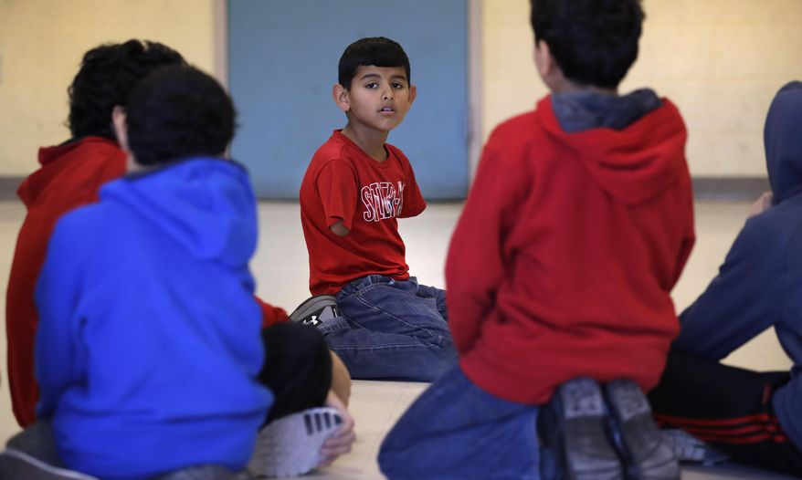 In this Dec. 10, 2016 photo, Syrian refugee Ahmad Alkhalaf kneels with friends after praying during a day camp for local Muslim children in Sharon, Mass. The young boy who lost his arms in a refugee camp bomb blast is thriving in his new life in Massachusetts. (AP Photo/Charles Krupa)