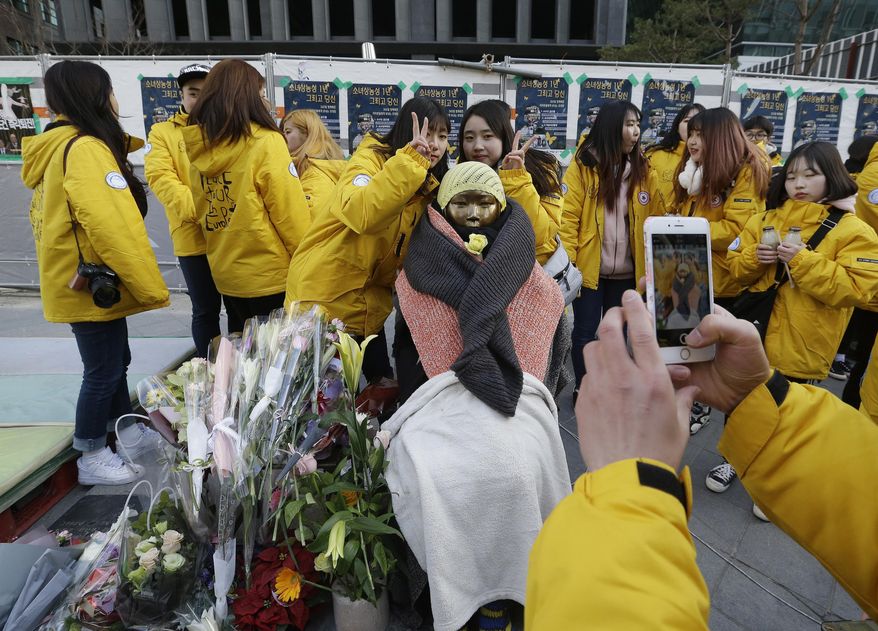 In this Wednesday, Dec. 28, 2016 photo, college students take pictures with the statue of a girl representing victims of Japanese sexual slavery in front of the Japanese Embassy in Seoul, South Korea. South Korea's opposition politicians on Wednesday called for nullifying a settlement reached between Seoul and Tokyo on compensation for South Korean women forced into sexual slavery by Japan's military in World War II. (AP Photo/Ahn Young-joon, File)