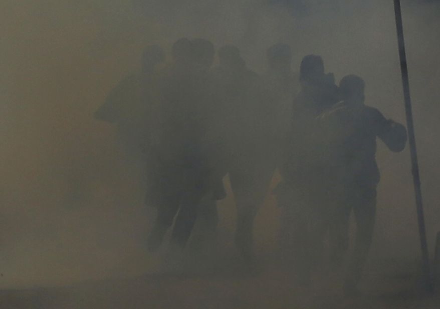 In this Friday, Dec. 30, 2016 photo, Kashmiri protesters run for cover amid tear gas smoke during a protest after Friday prayers in Srinagar, Indian controlled Kashmir. Police fired teargas and shotgun pellets to disperse Kashmiris who gathered after Friday afternoon prayers to protest against Indian rule in the disputed region. (AP Photo/Mukhtar Khan, File)
