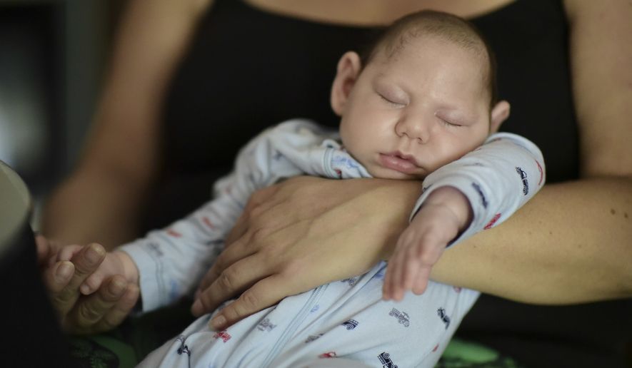 Two-month-old Inti Perez, diagnosed with microcephaly linked to the mosquito-borne Zika virus, is cradled by his mother in Bayamon, Puerto Rico. (Associated Press) ** FILE **