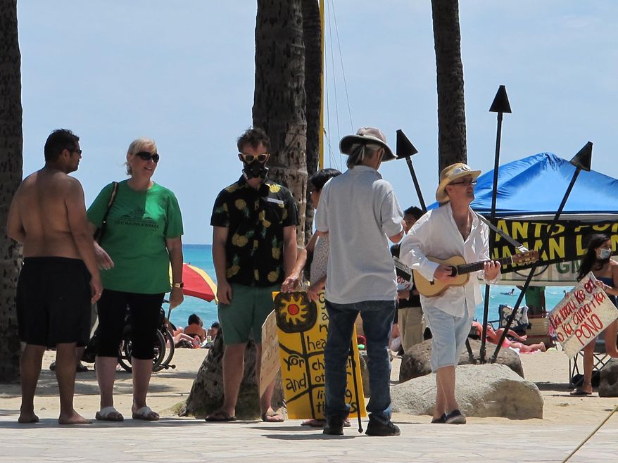 FILE - In this May 23, 2015, file photo, a man wearing a gas mask protests against Monsanto as a nearby ukulele player strummed a song at a Waikiki Beach rally in Honolulu. He was part of an international day of protests against the agriculture company. Hawaii residents concerned about pesticides are planning a push to strengthen regulation over chemicals they fear harm their health. (AP Photo/Cathy Bussewitz, File)
