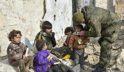 This undated handout photo released by the Russian Defense Ministry claims to show a Russian Military engineer distributing juice to local children in Aleppo, Syria.(Russian Defense Ministry Press Service photo via AP)