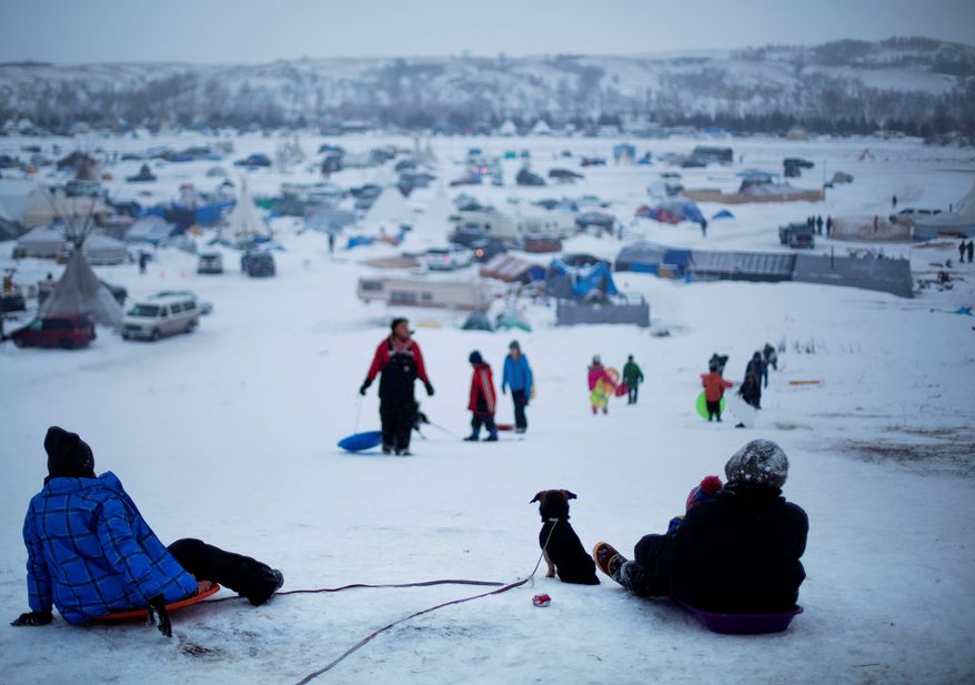 The Oceti Sakowin camp where people have gathered to protest the Dakota Access oil pipeline stands in the background as a children sled down a hill in Cannon Ball, N.D., in this Dec. 1, 2016, file photo. (AP Photo/David Goldman, File) **FILE**