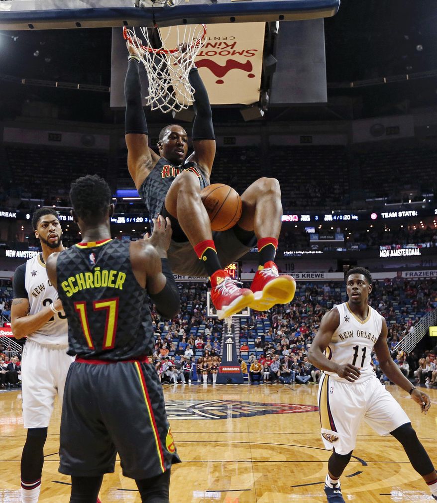 Atlanta Hawks center Dwight Howard, top, slam dunks between New Orleans Pelicans forward Anthony Davis and guard Jrue Holiday (11) in the first half of an NBA basketball game in New Orleans, Thursday, Jan. 5, 2017. (AP Photo/Gerald Herbert)