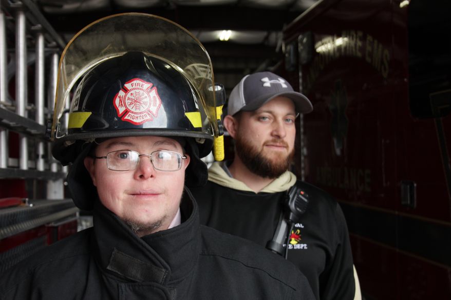 ADVANCE FOR USE SUNDAY, JAN. 8, 2017 AND THEREAFTER - In this Dec. 15, 2016 photo, Sandoval firefighter Jason Eagan, left, poses for a photo with Lt. Matt Horn at the firehouse in Sandoval, Ill. Jason, who is 33, has Down syndrome. There was concern in the department about Jason joining the force but he passed the firefighters' physical, paperwork was filled out, and it became official: Jason was a firefighter. He serves under cadet guidelines, and doesn't go into burning buildings or or engage in perilous rescues. But he is a firefighter. ( Brian Brueggemann/Belleville News-Democrat, via AP)