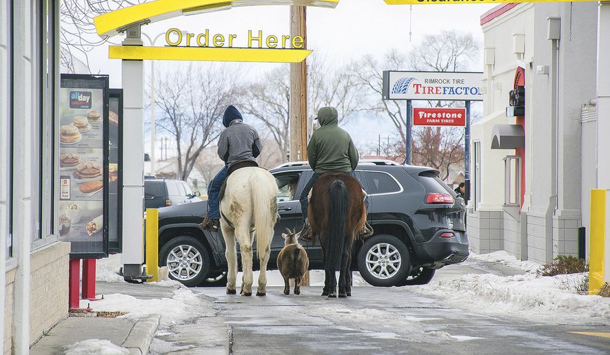 In this photo taken Dec. 30, 2016, Trajen Collins, left, is joined by Joel Perez as they ride their horses through the McDonald's drive-thru with a pet goat in tow in Powell, Wyo. The boys said they were bored during the holiday break and decided to ride their horses to town. The goat just followed, they said. (Toby Bonner/The Powell Tribune via AP)