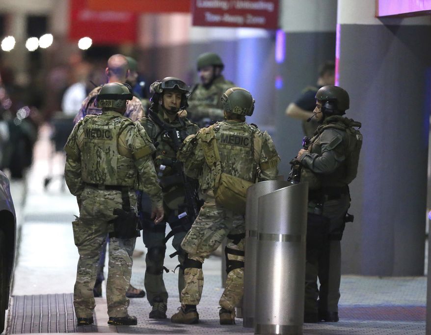 Police waiting to escort employees and passengers walking outside terminal 2 at the scene of a deadly shooting at Fort Lauderdale–Hollywood International Airport, Friday, January 6, 2017, in Fort Lauderdale, Fla. An Army veteran who complained that the government was controlling his mind drew a gun from his checked luggage on arrival at the Fort Lauderdale airport and opened fire in the baggage claim area Friday, killing several people and wounding others, authorities said. (David Santiago/El Nuevo Herald via AP)