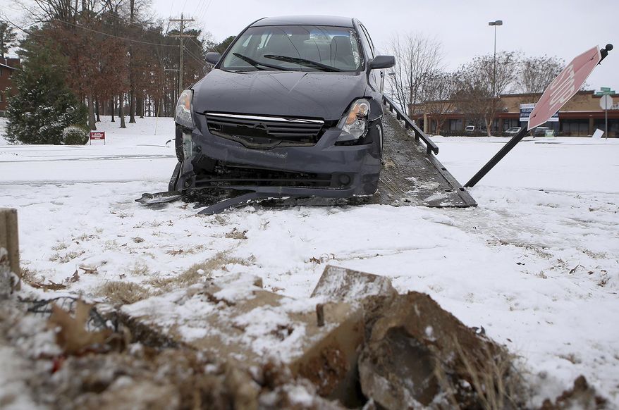 A car is loaded onto a flatbed wrecker after it crashed at the corner of Lanese Dockery Drive and Union University Drive in Jackson, Tenn., on Friday, Jan. 6, 2017. Police on scene said the car slid on the icy road. (C.B. Schmelter/The Jackson Sun via AP)
