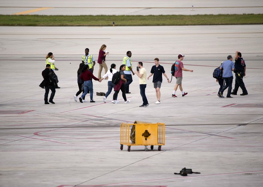 People are shown on the tarmac at Fort Lauderdale–Hollywood International Airport, Friday, Jan. 6, 2017, in Fort Lauderdale, Fla. A gunman opened fire in the baggage claim area at the airport Friday, killing several people and wounding others before being taken into custody in an attack that sent panicked passengers running out of the terminal and onto the tarmac, authorities said. (AP Photo/Wilfredo Lee)