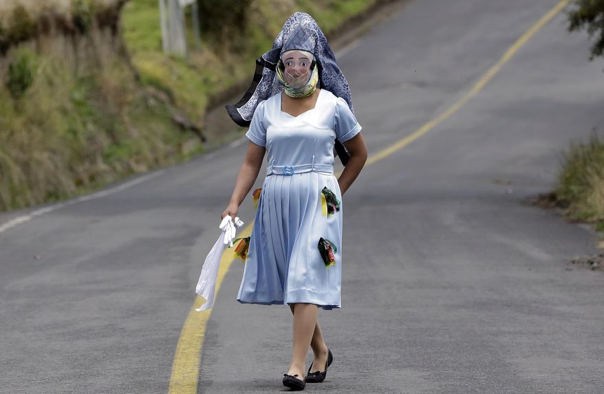 A woman dressed for la "La Diablada" festival, walks down a road in Pillaro, Ecuador, Friday, Jan. 6, 2017. Local legend holds that anyone who adopts a costume for the celebration and wears it at the event six years in a row will have good luck. (AP Photo/Dolores Ochoa)