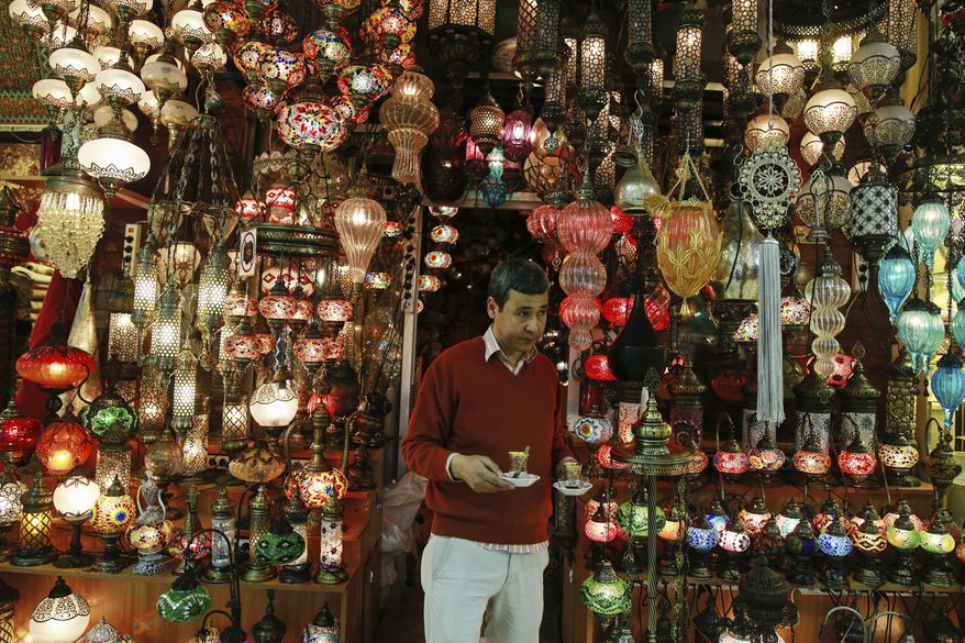 In this Thursday, Jan. 5, 2017 photo, a shop owner holds cups of tea outside his shop in Istanbul's Grand Bazaar, one of Istanbul's main tourist attractions. Turkey's economy is suffering in the face of a string of extremist attacks _ including the nightclub massacre of New Year’s revelers, most of them foreigners _ and uncertainty following the failed coup in July against President Recep Tayyip Erdogan that saw more than 270 people killed. (AP Photo/ Emrah Gurel)