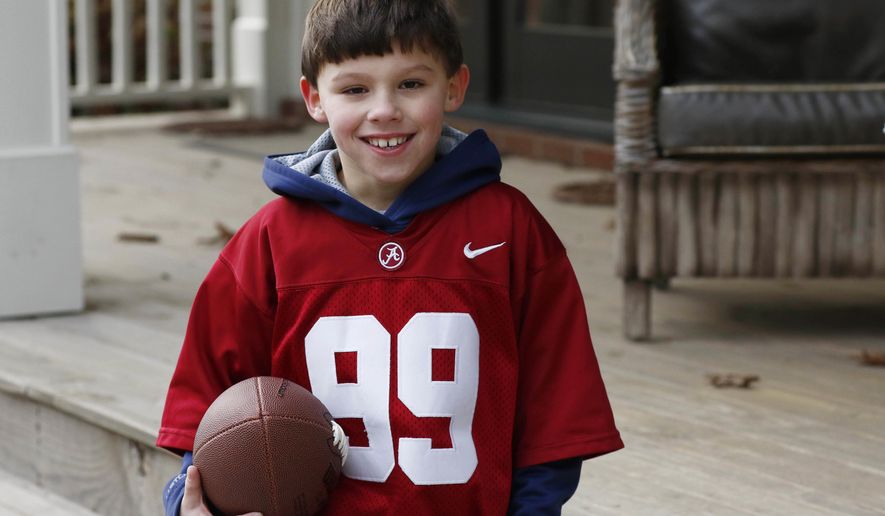 In this Friday, Jan. 6, 2017 photo, Boone Murphree, 8, poses after an afternoon of punting and passing the football with his family, Friday, Jan. 6, 2017, in Tupelo, Miss., shares unusual bonds with Alabama kicker Adam Griffith besides football. They are originally from Poland, they lived for a while in an orphanage and both were adopted by Southern families.The two met at Alabama&#39;s 2015 spring football game and established a friendship that Murphree takes seriously. (AP Photo/Rogelio V. Solis)
