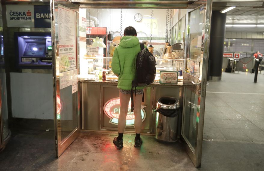 A passenger buys a slice of pizza while taking part in the No Pants Subway Ride in Prague, Czech Republic, Sunday, Jan. 8, 2017. The No Pants Subway Ride began in 2002 in New York as a stunt and has taken place in cities around the world since then. (AP Photo/Petr David Josek)