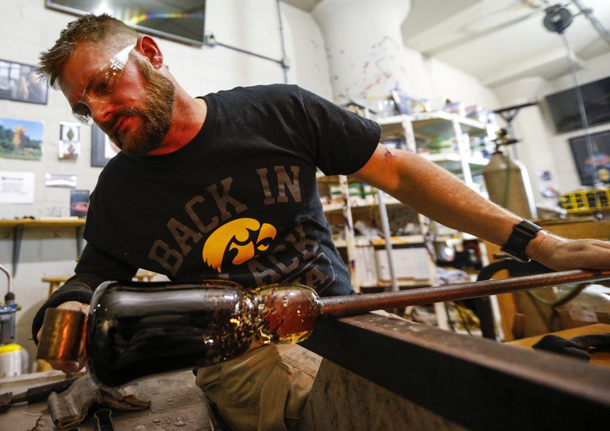 ADVANCE FOR THE WEEKEND OF JAN. 7-8 AND THEREAFTER - In a Dec. 21, 2016 photo, Mark Van Osdel of Le Claire uses a paddle to shape the base of his vase and prep it to transfer from the pipe to a ponty at Hot Glass studio in Davenport. Van Osdel is a veteran who is currently learning the art form from Joel Ryser who runs Hot Glass, a nonprofit organization and business in Davenport that offers free glass-blowing classes to veterans and at-risk children. (Andy Abeyta/Quad City Times via AP)
