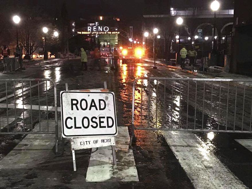 In this Saturday Jan. 7, 2017 photo, City of Reno crews close flood-prone roads and bridges in Northern Nevada late Saturday, including the Lake Street bridge over the Truckee River by the old Reno Arch in downtown Reno, Nevada. The region's worst flooding in a decade is forecast Sunday night into Monday. (AP Photo/Scott Sonner)
