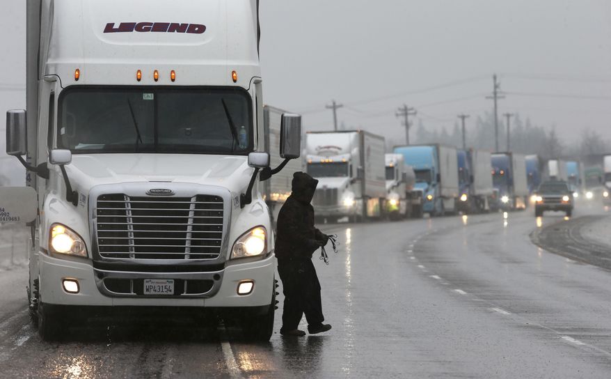 Semi-trucks line the shoulder of Interstate 5 south of Eugene, Ore. Sunday Jan. 8, 2017 as drivers chain up for the drive north through a winter storm. Snow and sleet are making for treacherous roads in Oregon, with the state police warning that they can't keep up with all the crashes. (Chris Pietsch/The Register-Guard via AP)