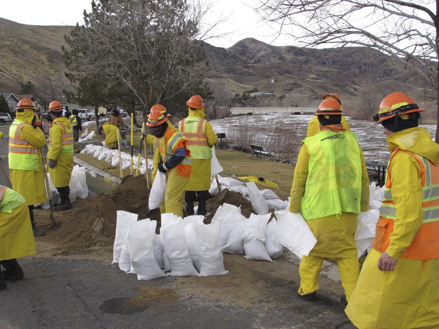 Emergency crews pile sandbags Monday, Jan. 9, 2017, along the Truckee River in Lockwood, Nev. National Guard troops were called in to assist local residents whose neighborhood was cut off by flooding. The worst danger had passed but more rain was in the forecast later this week. (AP Photo/Scott Sonner)