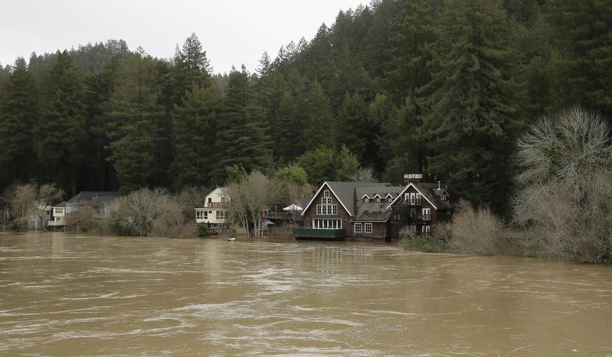 The Russian River flows just below cabins and a hotel Monday, Jan. 9, 2017, in Monte Rio, Calif. A massive storm system stretching from California into Nevada lifted rivers climbing out of their banks, flooded vineyards and forced people to evacuate after warnings that hillsides parched by wildfires could give way to mudslides. (AP Photo/Eric Risberg)