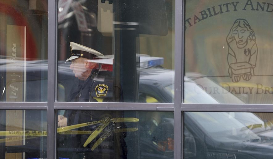 A Cincinnati police officer is seen through a window at Our Daily Bread Ministry in Over-the-Rhine in Cincinatti, Ohio, Monday, Jan. 9, 2017, after a Monday morning shooting. A gunman at the social services mission in Cincinnati killed a man and critically wounded a woman at the facility Monday, police said. (Cara Owsley/The Cincinnati Enquirer via AP)
