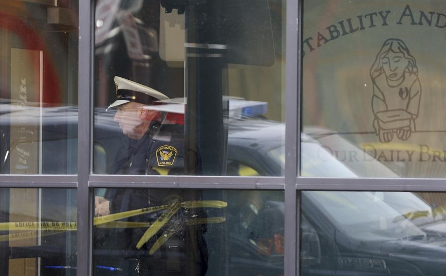 A Cincinnati police officer is seen through a window at Our Daily Bread Ministry in Over-the-Rhine in Cincinatti, Ohio, Monday, Jan. 9, 2017, after a Monday morning shooting. A gunman at the social services mission in Cincinnati killed a man and critically wounded a woman at the facility Monday, police said. (Cara Owsley/The Cincinnati Enquirer via AP)