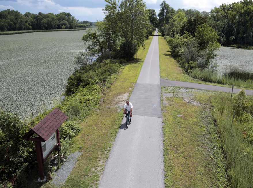 FILE- In this Tuesday, Aug. 4, 2015 file photo, a man bikes along the Canalway Trail in Niskayuna, N.Y. Under a proposal by New York Gov. Andrew Cuomo, the Canalway Trail will become part of a 750-mile paved biking and hiking Empire State Trail scheduled for completion by 2020. (AP Photo/Mike Groll, File)