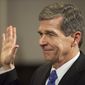 File-In this Jan. 1, 2017 photo Roy Cooper is sworn in as North Carolina governor shortly after midnight at the historic state Capitol Building in Raleigh, N.C. In politically divided North Carolina, weary voters hope top elected officials can put aside differences and effectively govern after a bruising election and a partisan tug-of-war that has spilled into court. (AP Photo/Ben McKeown, Pool)