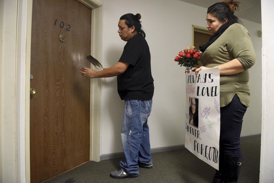In this Saturday, Jan. 7, 2017, photo, Franklin J. Whiting Jr. smudges outside of Jamie Lee Wounded Arrow's apartment after she was found dead, as Dorene Sabal-Camacho, right, holds a sign for a memorial used in a prayer service held at the apartment building in Sioux Falls, S.D. Police say a man accused of fatally stabbing a transgender woman in Sioux Falls has been charged with murder and other counts. (Jay Pickthorn/The Argus Leader via AP)