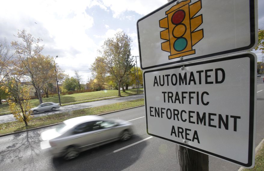 In this Oct. 29, 2014, file photo, motorists drive past a sign warning of upcoming traffic cameras in Cleveland. (AP Photo/Tony Dejak, File)
