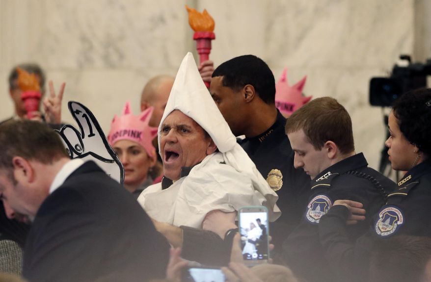 A protester is escorted away by Capitol Hill Police officers, Tuesday, Jan. 10, 2017, in Washington, during the Senate Judiciary Committee&#x27;s confirmation hearing for Attorney General-designate, Sen. Jeff Sessions, R-Ala. (AP Photo/Alex Brandon)