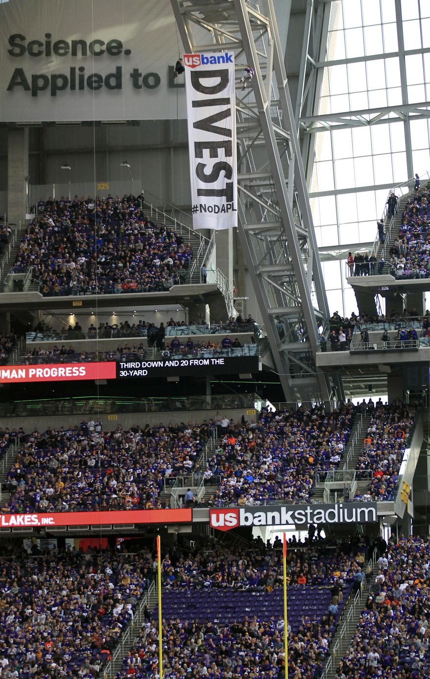 FILE -In this Jan. 1, 2017, file photo, protesters against the Dakota Access Pipeline rappel from the catwalk after placing a banner in U.S. Bank Stadium during an NFL football game between the Minnesota Vikings and Chicago Bears in Minneapolis. The front lines of the battle against the $3.8 billion Dakota Access pipeline are shifting away from the dwindling encampment in North Dakota. (AP Photo/Andy Clayton-King, File)