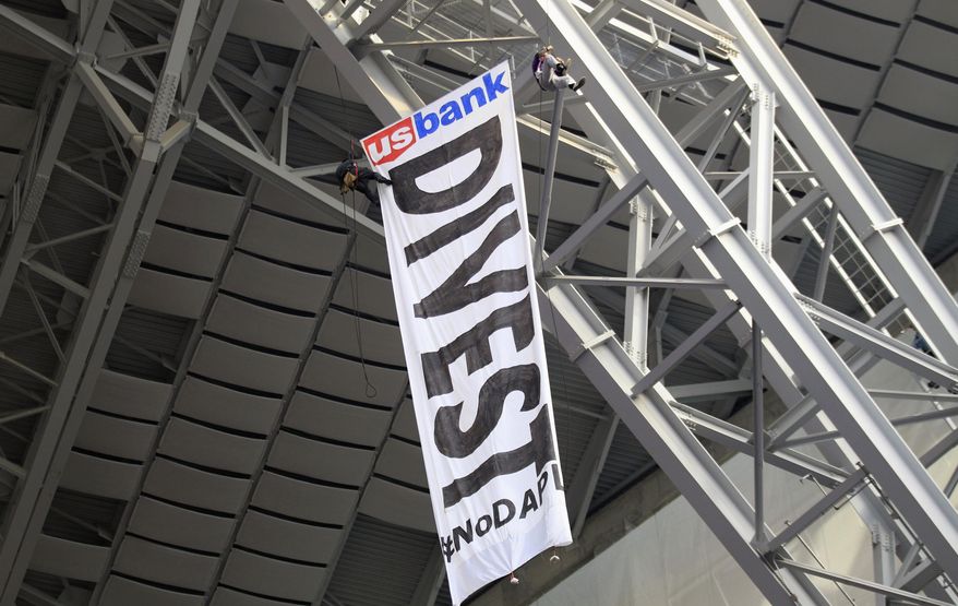 FILE - In this Jan. 1, 2017, file photo, protesters against the Dakota Access Pipeline rappel from the catwalk after placing a banner in U.S. Bank Stadium during an NFL football game between the Minnesota Vikings and Chicago Bears in Minneapolis. The front lines of the battle against the $3.8 billion Dakota Access pipeline are shifting away from the dwindling encampment in North Dakota. (AP Photo/Andy Clayton-King, File)