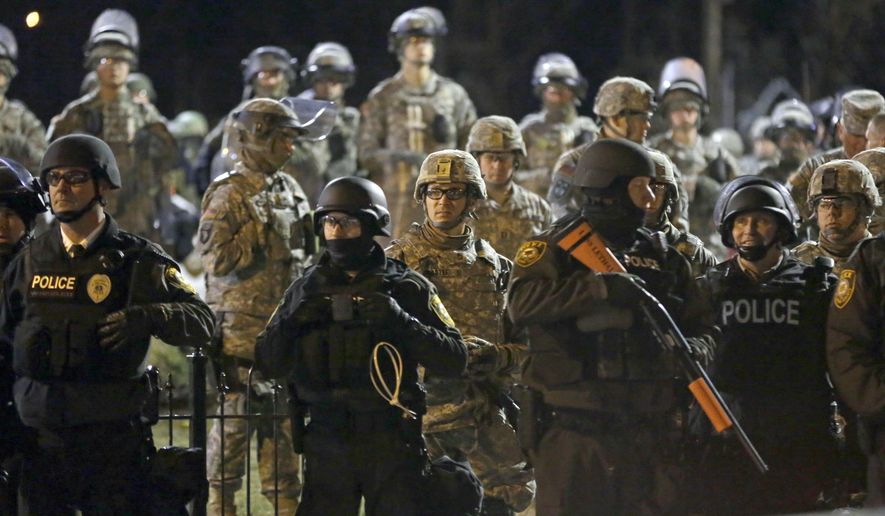 In this Friday, Nov. 28, 2014, file photo, police and Missouri National Guardsmen stand guard as protesters gather in front of the Ferguson Police Department, in Ferguson, Mo. The so-called "Ferguson effect" — officers backing off of policing out of fear that their actions will be questioned after the fact — has been talked about but never really quantified. A new study suggests the effect is a reality, with three-quarters of officers surveyed saying they are hesitant to use force, even when appropriate, and are less willing to stop and question suspicious people. (AP Photo/Jeff Roberson, File)