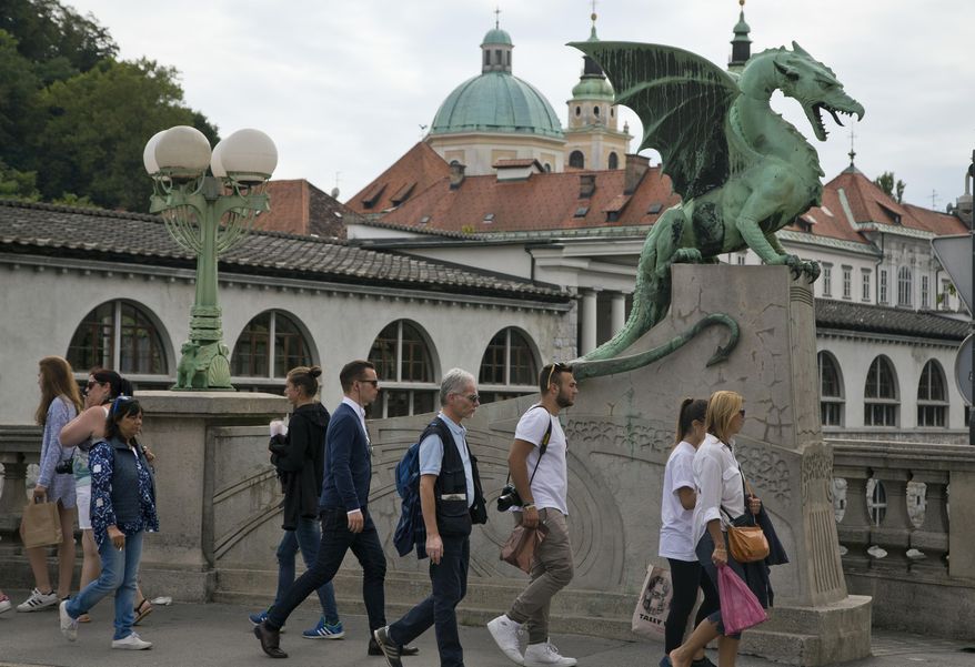 FILE- In this Aug. 12, 2016 photo, tourists and residents walk by a statue of a dragon, a symbol of the city, in downtown Ljubljana, Slovenia. The tiny European nation of Slovenia is getting an outsize share of attention lately. Not only has Melania Trump, wife of U.S. President-elect Donald Trump. given her native country a boost of recognition, but Slovenia’s also in the midst of a tourism boom. (AP Photo/Darko Bandic, File)