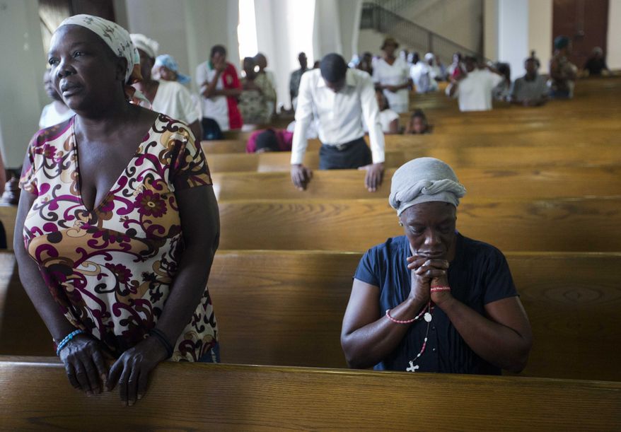 In this Thursday, Jan. 12, 2017 photo, residents attend a Mass during the 7th anniversary of the earthquake in Port-au-Prince, Haiti. Many Haitians lit candles and offered prayers Thursday to remember relatives and neighbors who died in a catastrophic earthquake that struck near the Caribbean nation's capital seven years ago.(AP Photo/Dieu Nalio Chery)