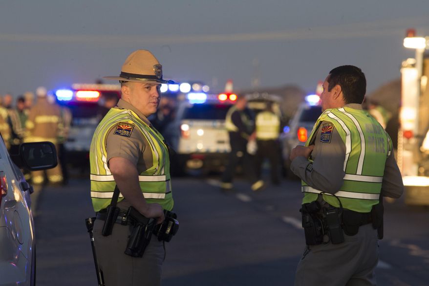 Emergency personnel gather at the scene where an Arizona Department of Public Safety trooper was shot, Thursday, Jan. 12, 2017, at the scene of a rollover accident on Interstate 10 near Tonopah, Ariz. An Arizona state trooper stopped to help at a car wreck along the remote highway Thursday when he was shot and wounded in an ambush by a man who was bashing the officer's head against the pavement until a passing driver shot him to death, authorities said. The trooper suffered a severe wound to his shoulder and upper chest but he is expected to recover at a hospital.(Mark Henle/The Arizona Republic via AP)