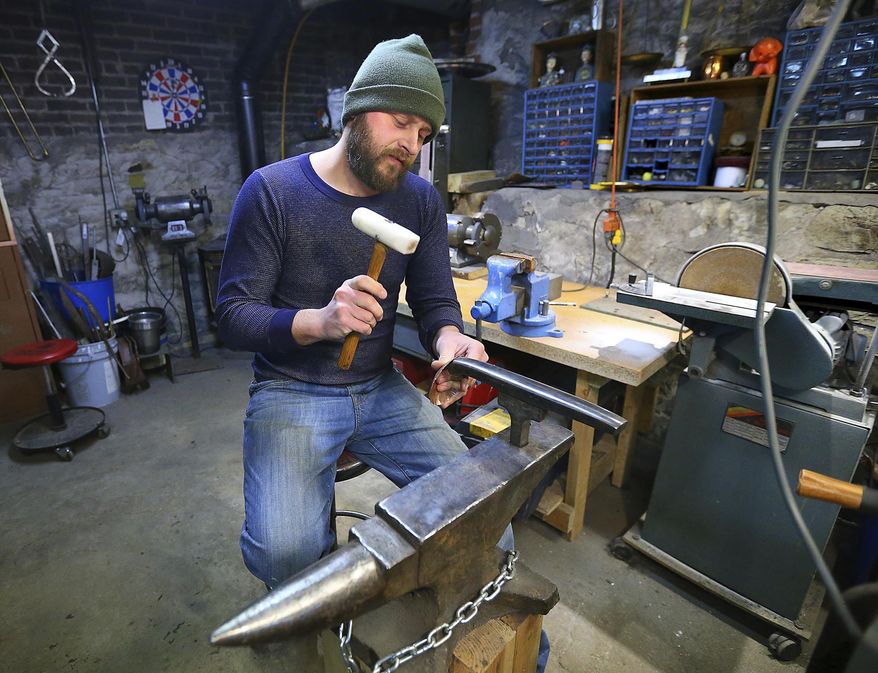 In this Jan. 9, 2017 photo, Adam Oldre works a piece of metal in his shop, in La Crosse, Wis. Oldre creates vessels and jewelry from recycled and repurposed metals. Oldre has been invited to participate in the American Concern for Artistry and Craftsmanship's ACAC Annual Craft and Fine Art Festival in New York, a prestigious juried show. (Erik Daily /La Crosse Tribune via AP)