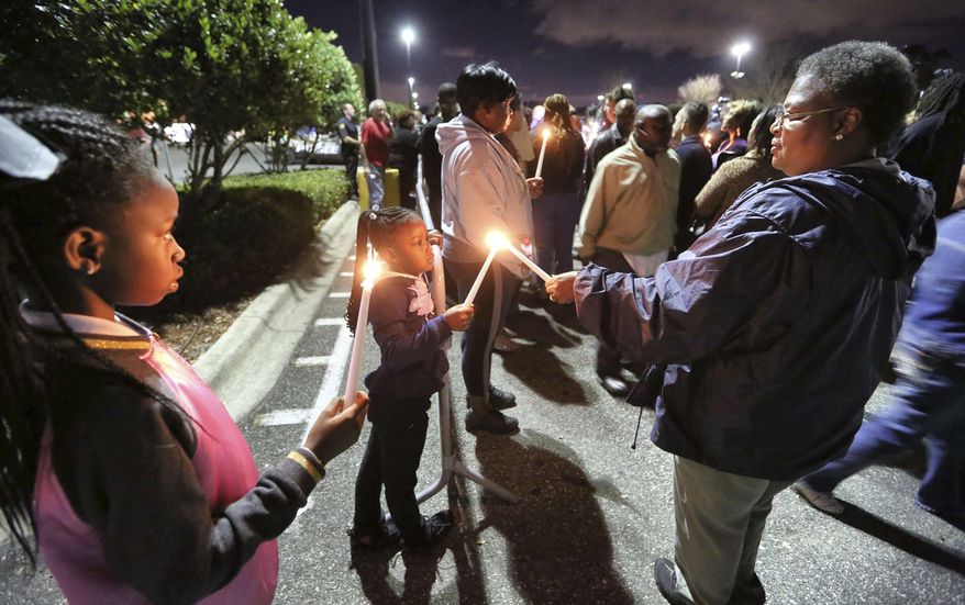 Nine-year-old Nyasia Bell, from left, 6-year-old Nahla Bell and their aunt, Evelyn McKay, light candles during a vigil at a Wal-Mart store, where an Orlando police sergeant was killed Monday, and for an Orange County Sheriff's Office deputy killed during a manhunt of a suspect, in Orlando, Fla., Tuesday, Jan. 10, 2017. Authorities raised to $100,000 the reward for information leading to the arrest of the suspect in the fatal shooting of the Orlando police sergeant on Tuesday as he eluded hundreds of officers on the second day of a massive manhunt. (Joe Burbank/Orlando Sentinel via AP)
