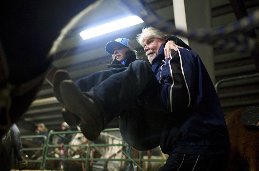 Cory Snyder lifts his daughter Amberley up onto the saddle of her horse named Legacy, also known as French Open, before competing in the Dash for Cash barrel races Friday, Jan. 7, 2017 at the Spanish Fork fairgrounds in Spanish Fork, Utah. Snyder has no feeling in her legs, but the barrel-racer isn't letting that slow her down. (Isaac Hale /The Daily Herald via AP)