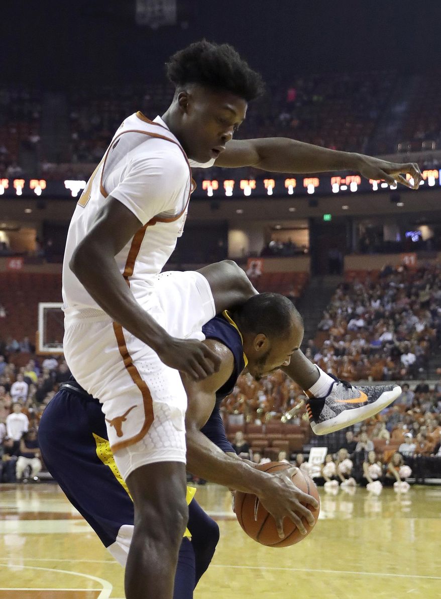 Texas guard Andrew Jones (1) lands on West Virginia guard Jevon Carter (2) as they chase a rebound during the first half of an NCAA college basketball game, Saturday, Jan. 14, 2017, in Austin, Texas. (AP Photo/Eric Gay)
