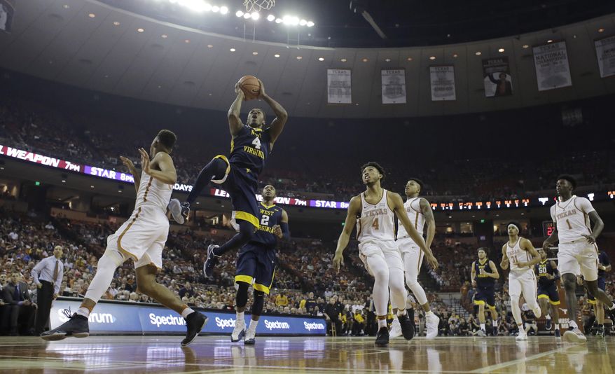 West Virginia guard Daxter Miles Jr. (4) drives between Texas defenders Eric Davis Jr. (10) and James Banks (4) during the first half of an NCAA college basketball game, Saturday, Jan. 14, 2017, in Austin, Texas. (AP Photo/Eric Gay)