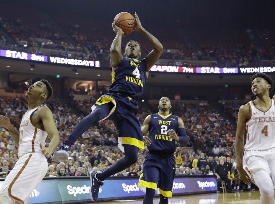 West Virginia guard Daxter Miles Jr. (4) drives between Texas defenders Eric Davis Jr. (10) and James Banks (4) during the first half of an NCAA college basketball game, Saturday, Jan. 14, 2017, in Austin, Texas. (AP Photo/Eric Gay)